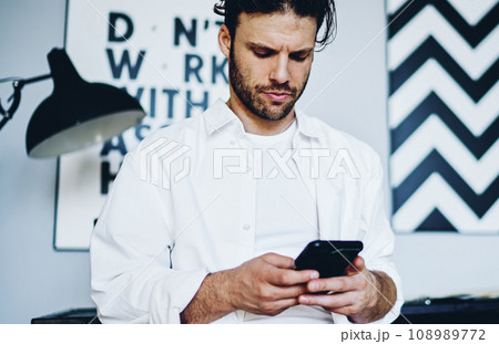 pensive hipster guy checking banking balance via mobile phone for making money transaction pensive hipster guy checking banking balance via mobile phone for making money transaction 108989772