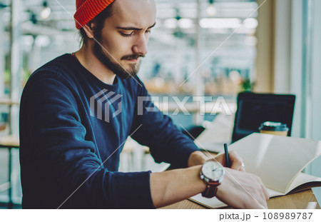 caucasian man in stylish apparel making notes of information in notepad for education caucasian man in stylish apparel making notes of information in notepad for education 108989787