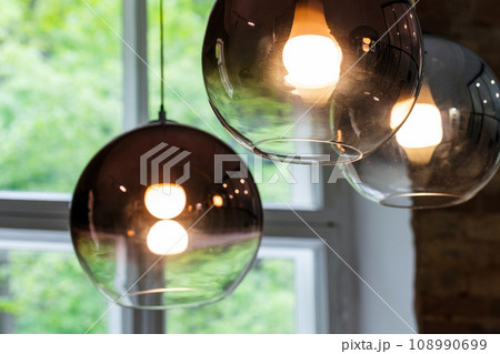 Round glass lampshades with  glowing tungsten lamps inside 108990699