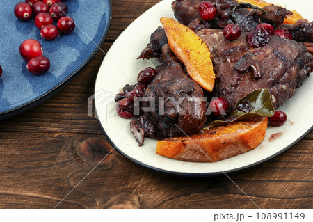 Baked chicken drumsticks with orange and berries. 108991149
