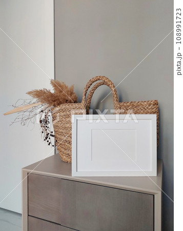Empty photo frame mockup on wooden table. Elegant workspace, home office concept. Scandinavian minimalistic interior design. Copy space for artwork, photo or print presentation. 108991723