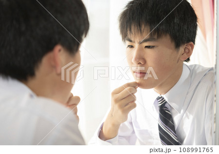 自宅の鏡で髭を気にする中学生の男の子 108991765