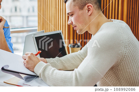 Pensive young man signing working documents which holding pretty cheerful secretary 108992086