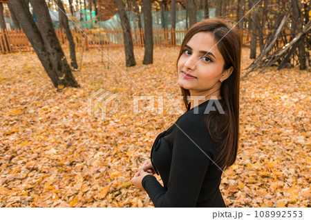Close-up portrait of diversity young beautiful confident Indian Asian woman in black dress in fall outdoor copy space mockup. Happy and natural smiling female. Generation z and gen z youth concept Close-up portrait of diversity young beautiful confident Indian Asian woman in black dress in fall outdoor copy space mockup. Happy and natural smiling female. Generation z and gen z youth concept 108992553