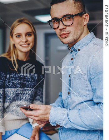 Two hipster students standing in coworking space.Young man with cellular in hand 108993023