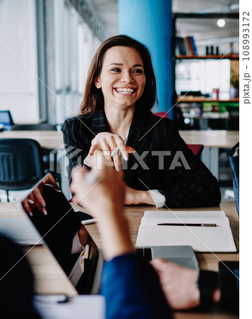 Cheerful male and female colleagues celebrating successful accomplished of project sitting at table 108993172