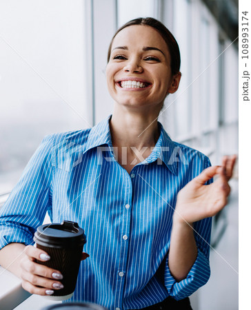 cheerful attractive female manager holding coffee cup and smiling enjoying career 108993174