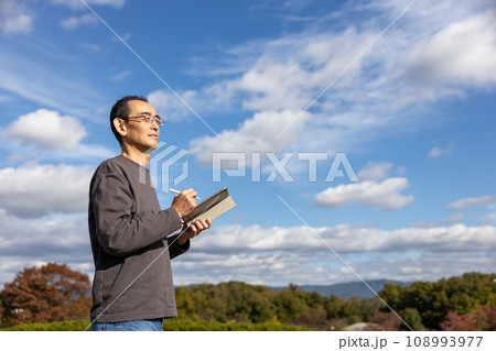 屋外でタブレットを持って立っている中高年男性 108993977