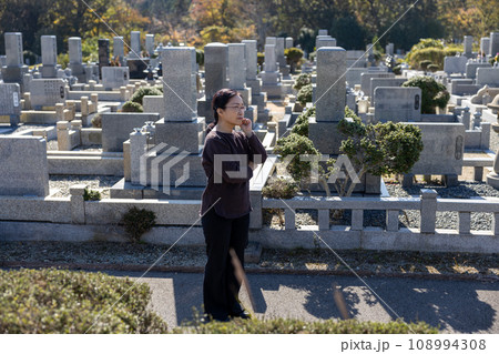 墓参りに来て考え込んでいる中高年女性 108994308