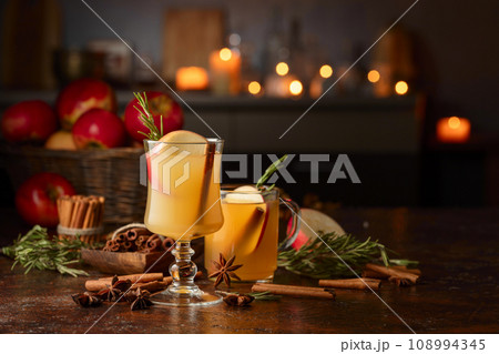 Mulled cider with apples, cinnamon, rosemary, and anise on a background of burning candles. 108994345