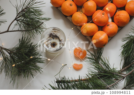 Candle, tangerines and pine. Christmas background with fir tree branches and tangerines merry christmas and happy new year. Candle, tangerines and pine. Christmas background with fir tree branches and tangerines merry christmas and happy new year. 108994811