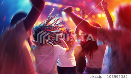 Happy, overjoyed people, students dancing raising hand and singing in neon light, spotlights indoor on party in motion blur. Happy, overjoyed people, students dancing raising hand and singing in neon light, spotlights indoor on party in motion blur. 108995382