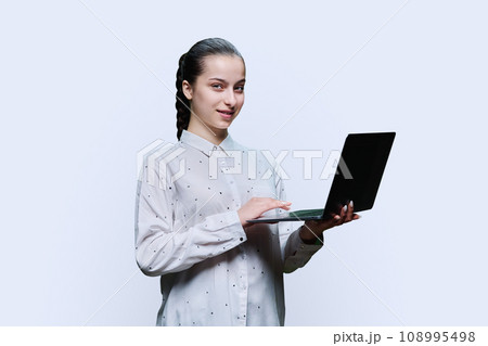 Smiling teenage high school student girl using laptop on white background 108995498