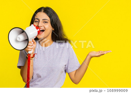 Indian woman talking with megaphone, proclaiming news loudly announcing advertisement discounts sale Indian woman talking with megaphone, proclaiming news loudly announcing advertisement discounts sale 108999009