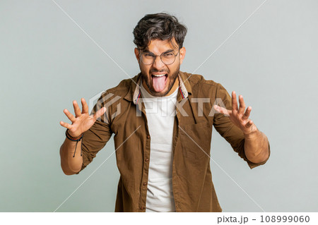 Cheerful funny bully Indian man showing tongue making silly faces, fooling around, joking, teasing Cheerful funny bully Indian man showing tongue making silly faces, fooling around, joking, teasing 108999060