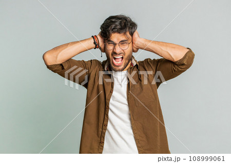 Annoyed irritated Indian man covering ears gesturing no avoiding advice ignoring noise loud voices Annoyed irritated Indian man covering ears gesturing no avoiding advice ignoring noise loud voices 108999061