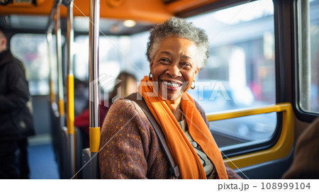 Affable smiling elderly passenger African American woman traveling through the city in bus, her bright attire and joyful expression lighting up the day Affable smiling elderly passenger African American woman traveling through the city in bus, her bright attire and joyful expression lighting up the day 108999104