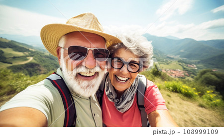 Happy senior couple making selfie, achievement of reaching the mountain summit, greenery and a panoramic view of the mountain range, story of active seniors embracing great outdoors Happy senior couple making selfie, achievement of reaching the mountain summit, greenery and a panoramic view of the mountain range, story of active seniors embracing great outdoors 108999109