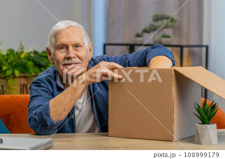 Happy senior grandfather man shopper unpack cardboard box delivery parcel online shopping purchase 108999179