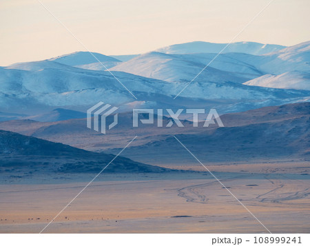 Layers of mountains on distance, soft pink sunset in mountain landscape. Layers of mountains background. Silhouette of the evening mountains at sunset. Layers of mountains on distance, soft pink sunset in mountain landscape. Layers of mountains background. Silhouette of the evening mountains at sunset. 108999241