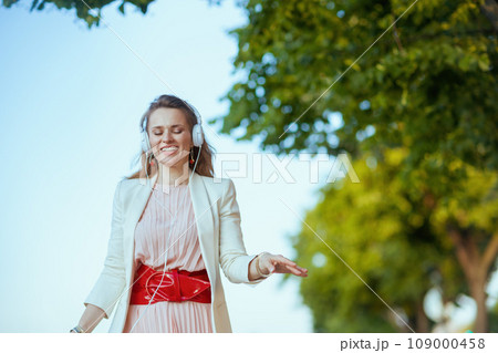 smiling trendy woman in city listening to music smiling trendy woman in city listening to music 109000458