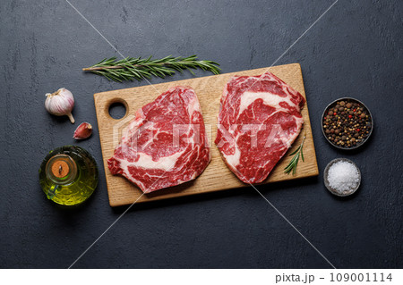 Raw ribeye steaks with savory spices 109001114