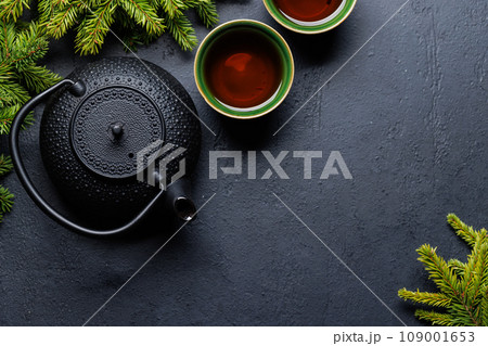 Teapot, cup, and fir tree branches create a cozy scene 109001653