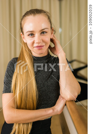 Portrait Female ballet dancer resting at barre and mirror in dance studio - dance and ballerina concept Portrait Female ballet dancer resting at barre and mirror in dance studio - dance and ballerina concept 109002039