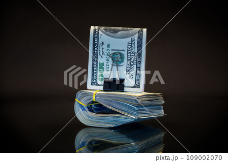 stack of dollar bills collected in an elastic band and a stationery clip stack of dollar bills collected in an elastic band and a stationery clip 109002070