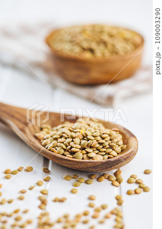 Uncooked lentil legumes in wooden spoon on white table. 109003290