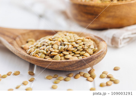 Uncooked lentil legumes in wooden spoon on white table. 109003291