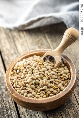 Uncooked lentil legumes in bowl on wooden table. Uncooked lentil legumes in bowl on wooden table. 109003298