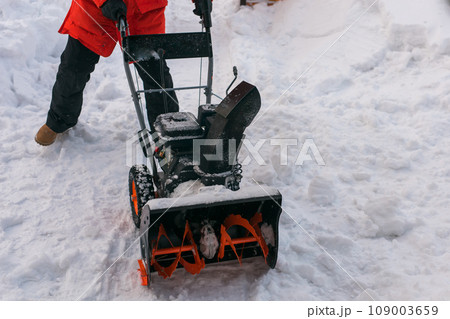 A man clear snow from backyard with snow blower close-up. Winter season and snow blower equipment A man clear snow from backyard with snow blower close-up. Winter season and snow blower equipment 109003659