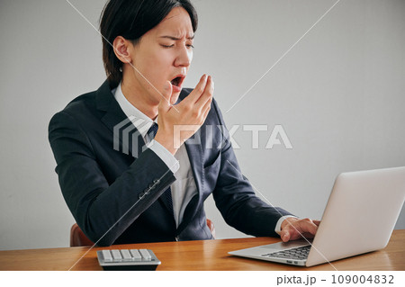 眠くてあくびをする若い男性会社員 109004832