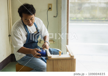 木の机をサンディングする男性　 109004835