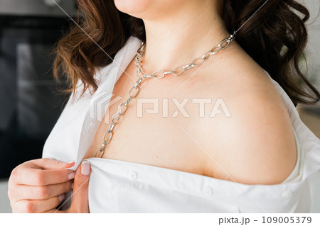 Close-up woman wears massive chain on neck, metal necklace. Modern jewellery concept Close-up woman wears massive chain on neck, metal necklace. Modern jewellery concept 109005379