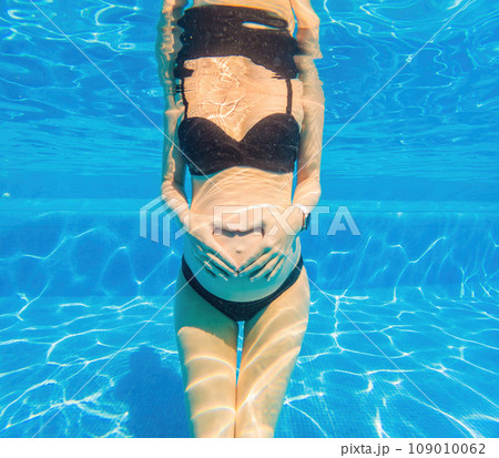 Pregnant bliss unfolds underwater as a woman forms a heart with her hands a serene and joyful aquatic moment celebrating life and love 109010062