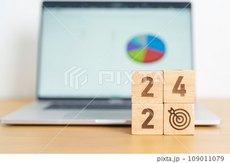 2024 Year block with dartboard icon against computer laptop background. Goal, Target, Resolution, strategy, plan, Action, mission, motivation, and New Year start concepts 109011079