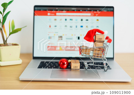 Christmas Online Shopping concept. Boxes with shopping cart on a laptop computer. Sale and discount during Christmas and New Year holiday, ecommerce, shipping delivery, logistics and Cyber Monday 109011900