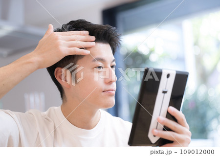 髪の生え際を気にする若い男性 髪の生え際を気にする若い男性 109012000