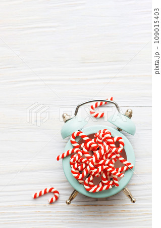 Christmas background with candy canes on alarm clock on wooden background 109015403