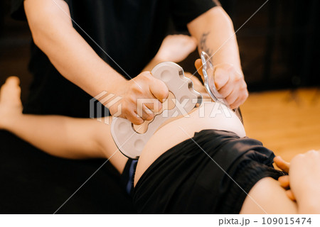 Massage with a special massage paddle, kneading trigger points in the abdomen, close-up. Blade massage. Side view. High quality photo Massage with a special massage paddle, kneading trigger points in the abdomen, close-up. Blade massage. Side view. High quality photo 109015474