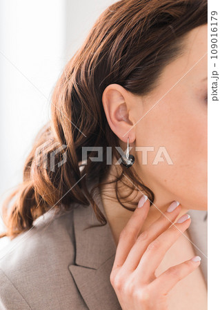 Detail of young woman wearing beautiful luxury earring close-up. Handmade jewellery and accessories Detail of young woman wearing beautiful luxury earring close-up. Handmade jewellery and accessories 109016179