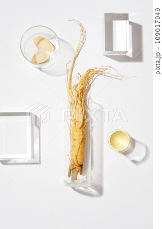Minimal scene for advertising and branding product with herbal ingredient from korean. A fresh ginseng on glass vase decorated with some glass podiums on white background Minimal scene for advertising and branding product with herbal ingredient from korean. A fresh ginseng on glass vase decorated with some glass podiums on white background 109017949