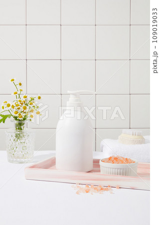 A marble tray feature a pump bottle and a bowl of pink himalayan salt. Pink Himalayan salt is less processed than table salt. Branding mockup design 109019033