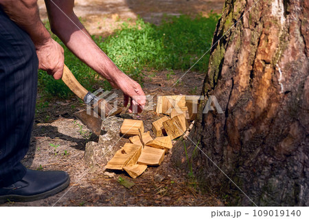 Hands of a man chopping wood with an axe at a picnic Hands of a man chopping wood with an axe at a picnic 109019140
