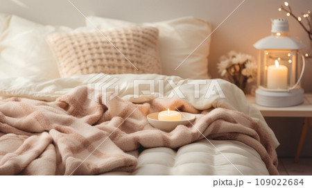 A cozy bed with fluffy blankets and pillows is visible in a warm and inviting bedroom 109022684