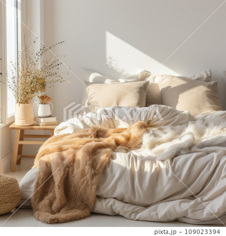 A cozy bed with fluffy blankets and pillows is visible in a warm and inviting bedroom A cozy bed with fluffy blankets and pillows is visible in a warm and inviting bedroom 109023394