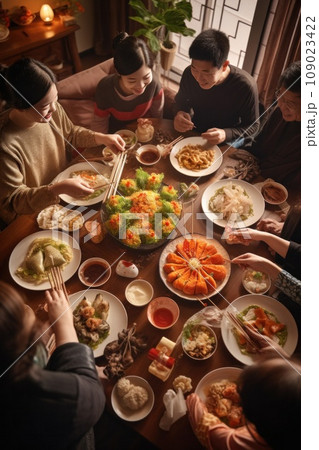 A family gathered around a table, enjoying a traditional Chinese New Year feast featuring dumplings A family gathered around a table, enjoying a traditional Chinese New Year feast featuring dumplings 109023422