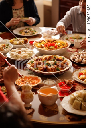 A family gathered around a table, enjoying a traditional Chinese New Year feast featuring dumplings A family gathered around a table, enjoying a traditional Chinese New Year feast featuring dumplings 109023480